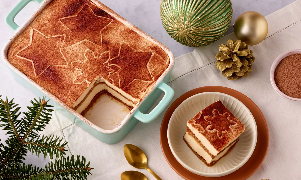 Spekulatius-Tiramisu in einer mintgrünen Form, mit Kakao bestäubt und weihnachtlichen Motiven, daneben ein Stück auf einem Teller angerichtet