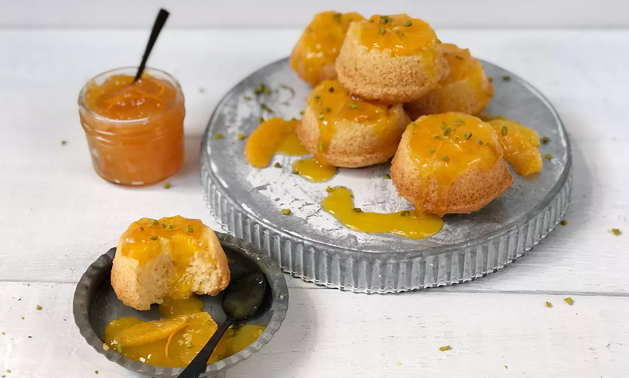 Vegane Küchlein mit karamellisierten Orangen und glänzendem Sirup, angerichtet auf einem silbernen Tablett, daneben ein Gläschen Marmelade