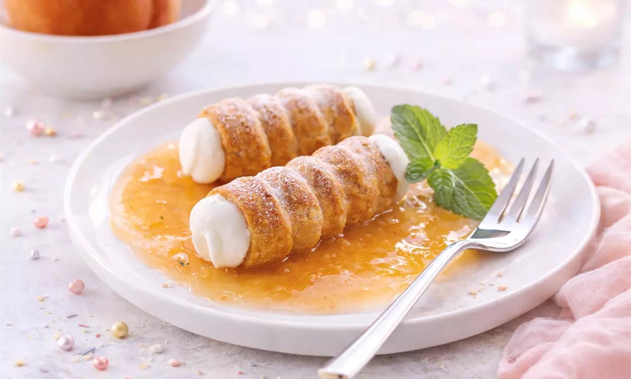 Köstliche Schaumröllchen auf Pfirsichmark! Dieses Rezept vereint eine luftig leichte Füllung mit fruchtiger Soße.