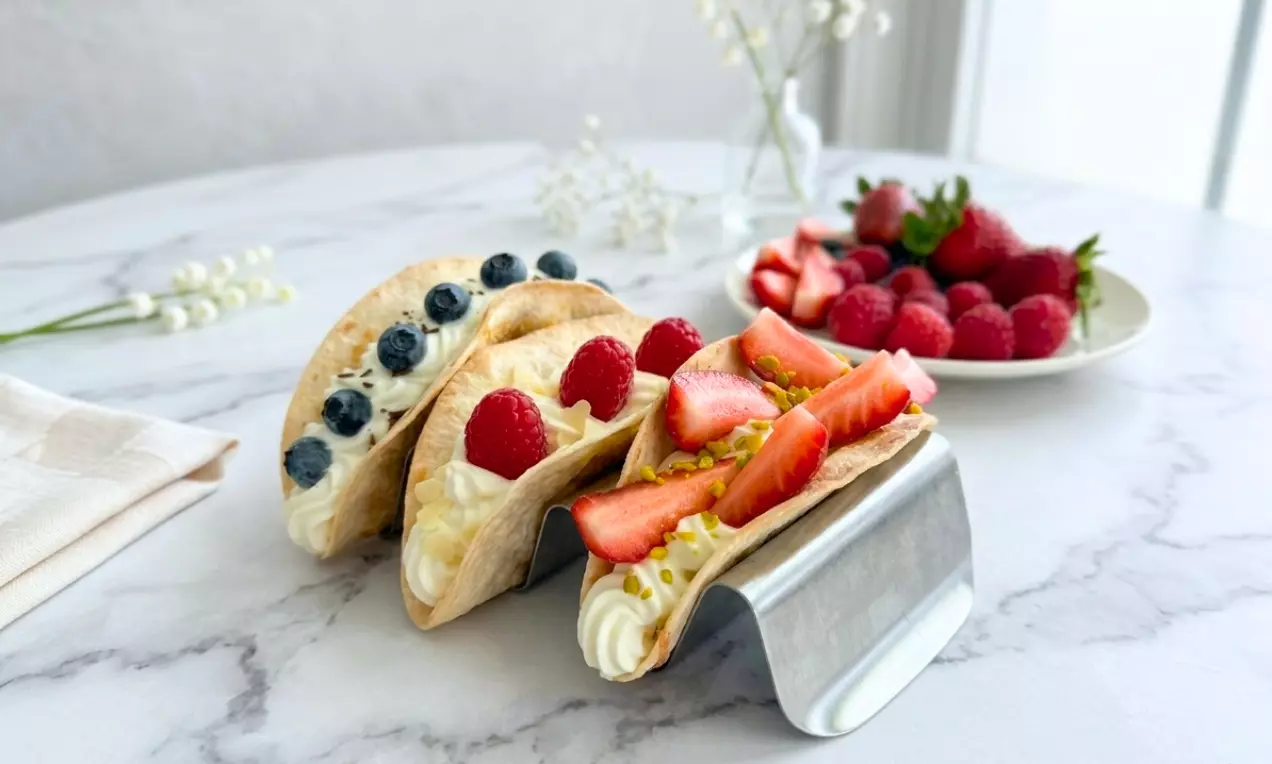Süße Tortilla-Schalen mit heller Cremefüllung, garniert mit frischen Beeren und Pistazien, präsentiert auf einem Metallhalter